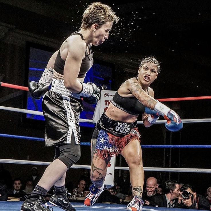 two female boxers in the ring during a boxing match, one is punching the other