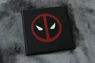 the deadpool logo is on top of a black book with red and white eyes