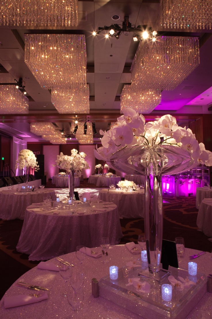 the tables are set with white flowers and crystal chandeliers