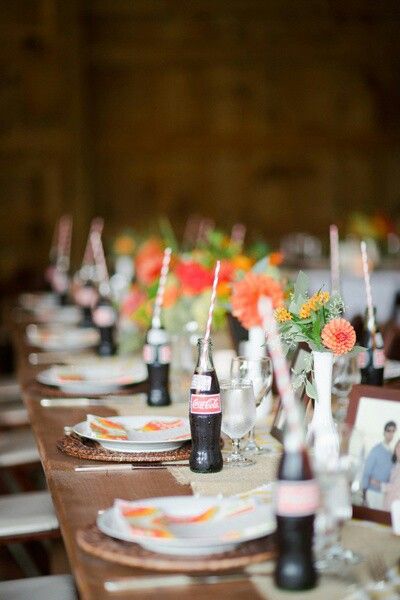 a long table is set with wine bottles and flowers in vases on the tables