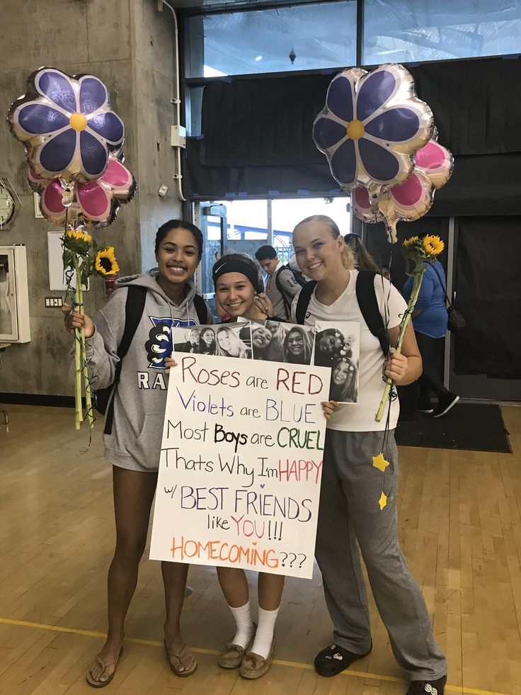 three people holding flowers and balloons in front of a sign that says roses are red