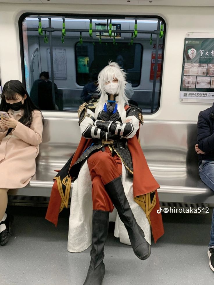 a person sitting on a subway train wearing a mask and holding a cell phone in their hand