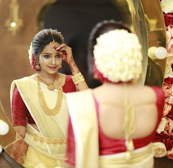 a woman standing in front of a mirror looking at herself in her wedding dress and jewelry