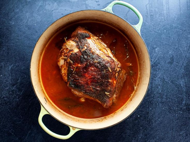 a pot filled with meat and sauce on top of a blue countertop next to a knife