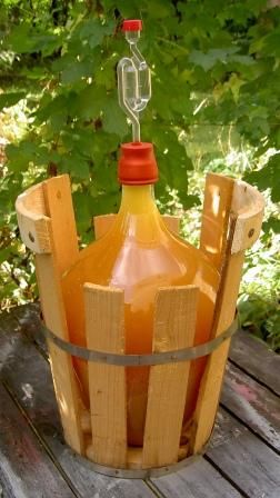 a wooden bucket filled with orange liquid sitting on top of a wooden table next to trees