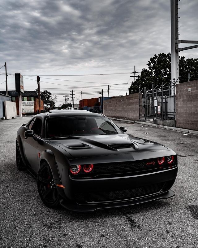 the black sports car is parked on the side of the road in an empty lot