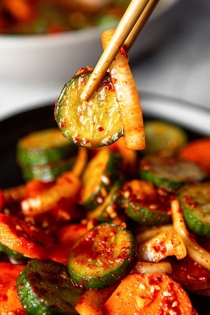 chopsticks picking up cooked vegetables from a bowl