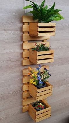 three wooden planters with plants in them on a wall next to a potted plant