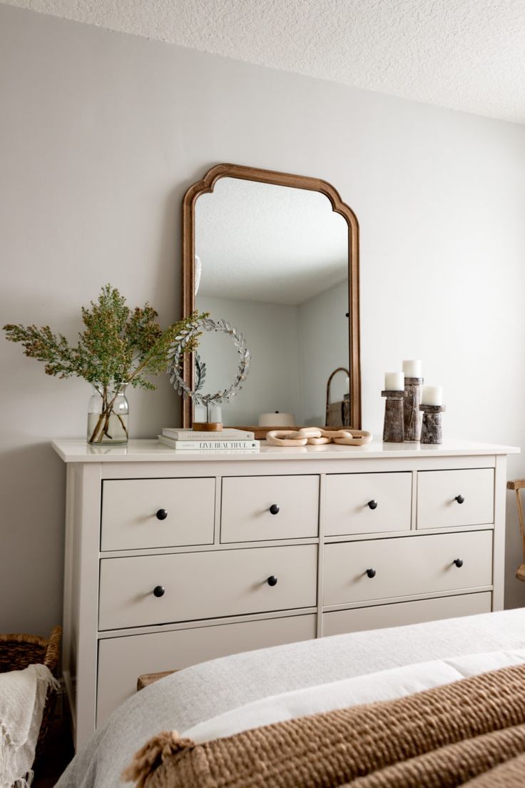 a bedroom with a white dresser and mirror