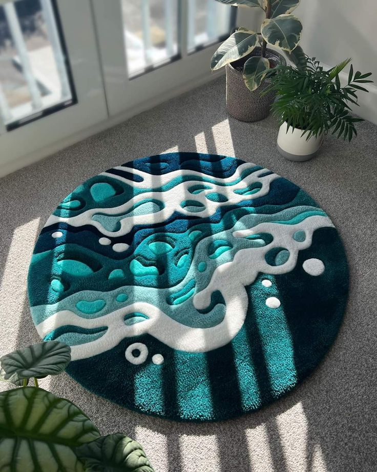 a round rug with blue and white designs on the floor next to a potted plant