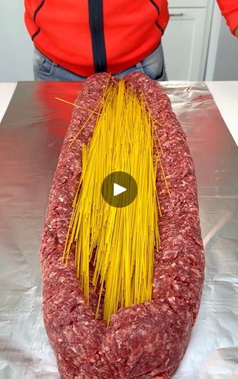 a large piece of meat sitting on top of a table next to a person in a red jacket