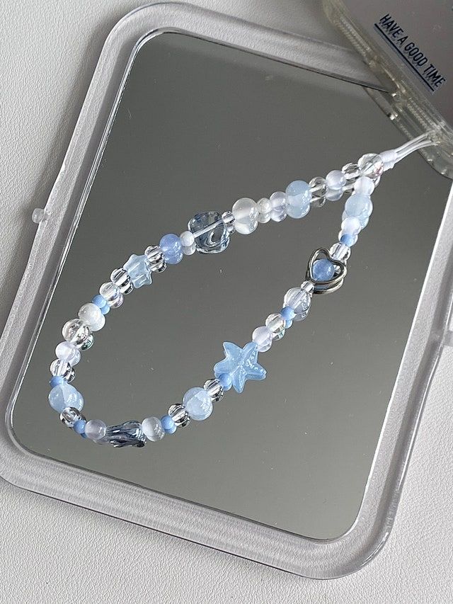 a blue and white beaded necklace sitting on top of a table next to a mirror