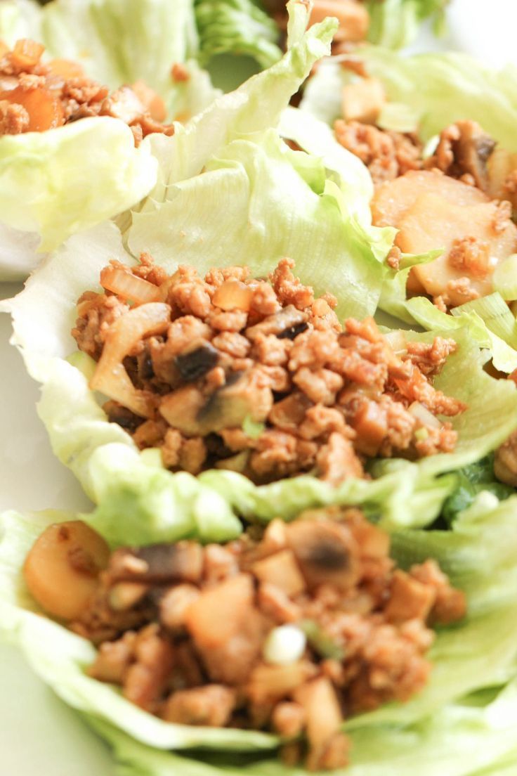 lettuce cups filled with meat and vegetables on a white plate, ready to be eaten