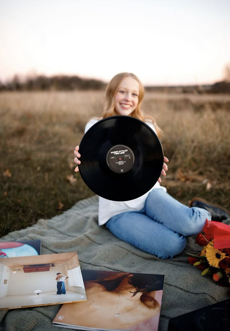 a woman sitting on the ground holding up a record