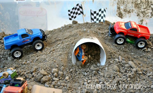 three toy trucks are parked in the middle of a pile of rocks