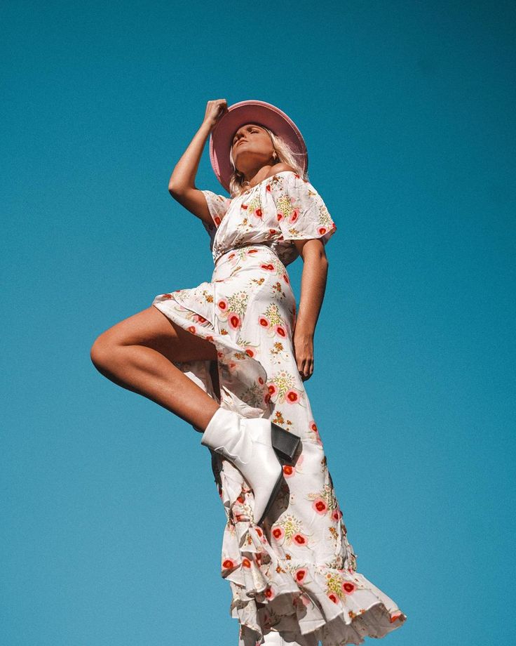 a woman in a dress and hat standing on her legs