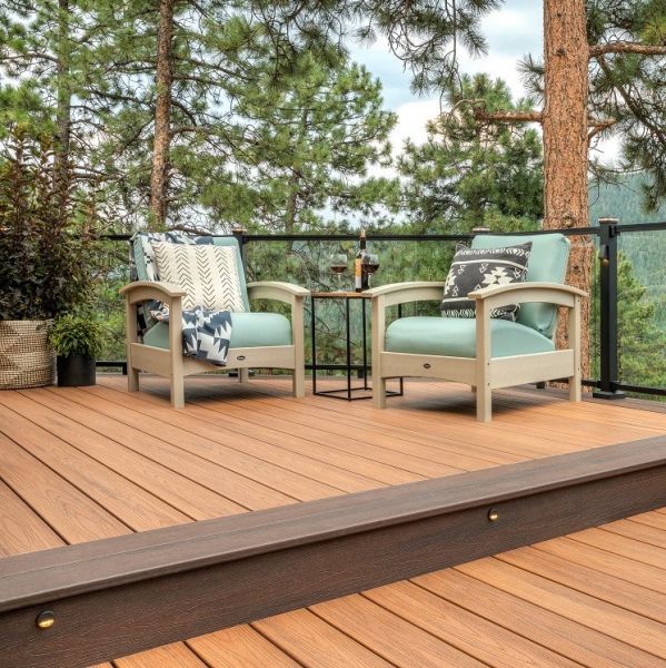 a deck with two chairs and a table on top of it next to some trees