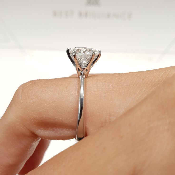 a woman's hand holding a diamond ring on her finger, with the center stone in