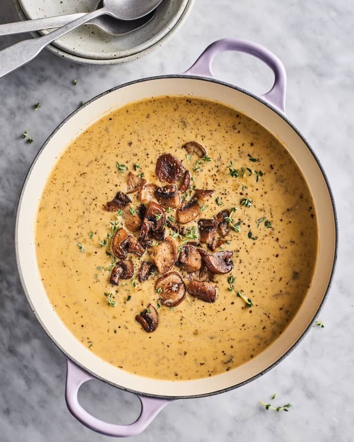 a bowl of soup with mushrooms in it on a marble counter top next to a spoon