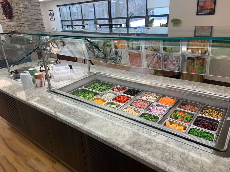 a salad bar with lots of different types of food on it in a restaurant or cafeteria