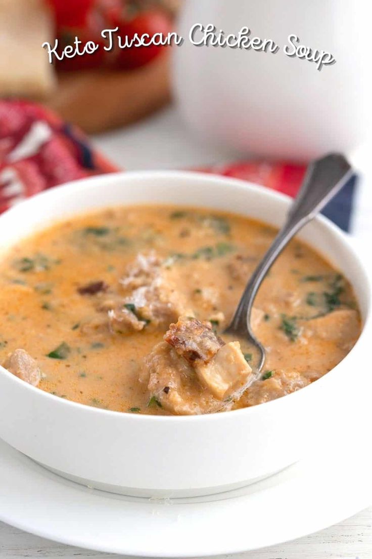 a white bowl filled with soup on top of a table next to a red napkin