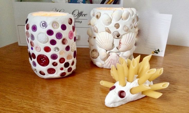 three ceramic vases sitting on top of a wooden table next to a notepad