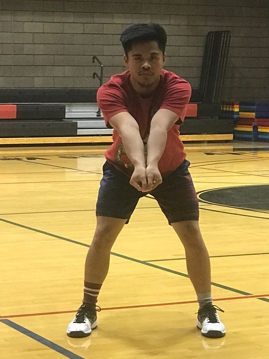 a man in red shirt and black shorts playing with a frisbee on an indoor court