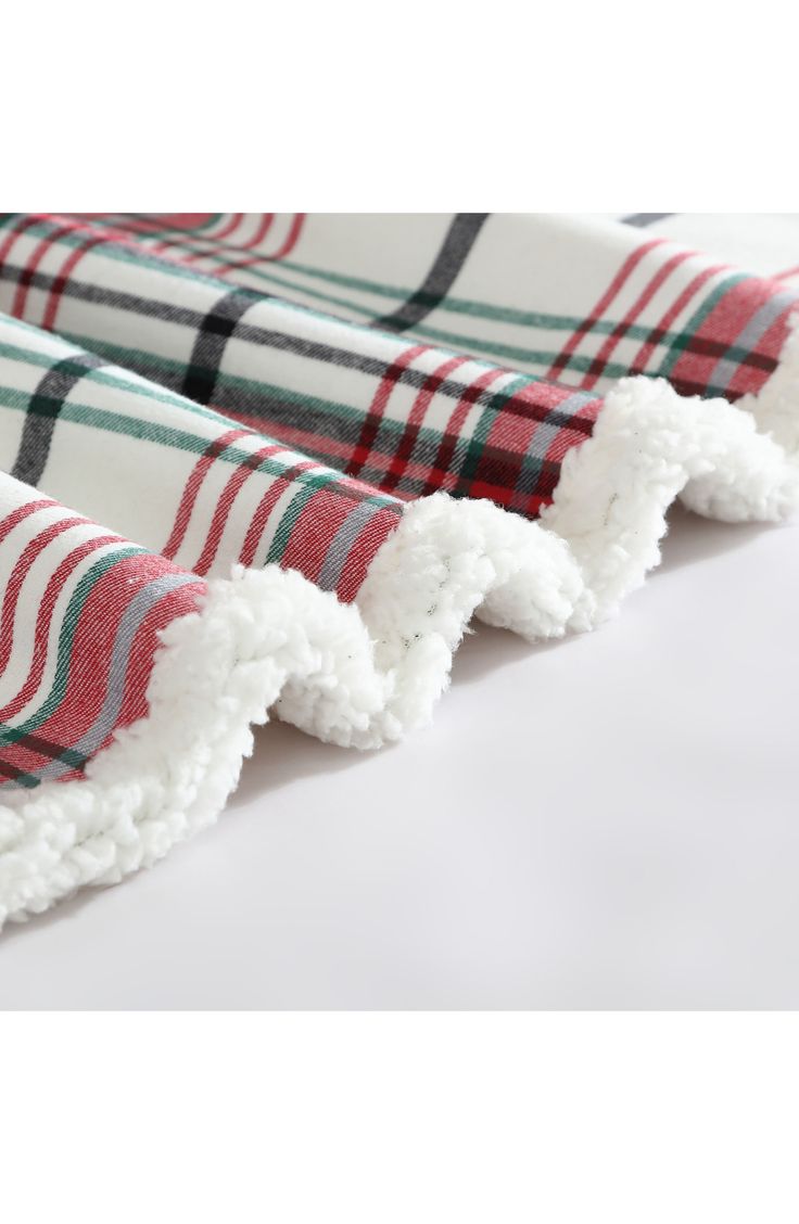 two red and green plaid towels folded on top of each other with pom - poms