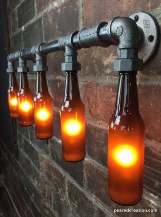 there are six bottles with lights in them hanging on the wall next to a brick wall