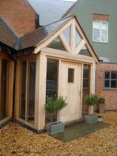 a small wooden building with potted plants in the front yard and windows on each side