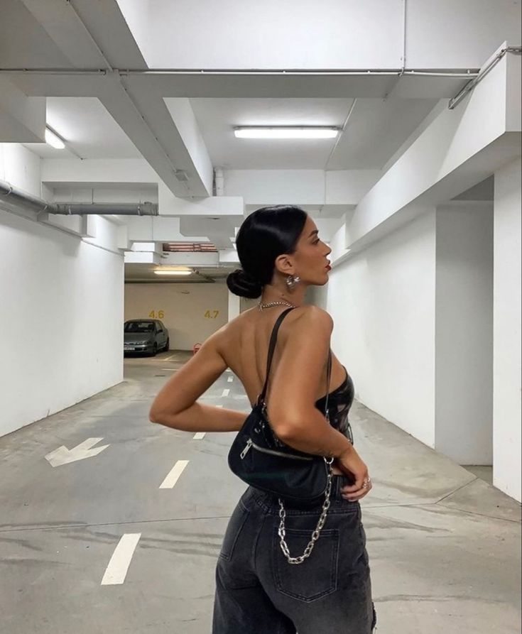 a woman standing in an empty parking garage with her back to the camera and looking up