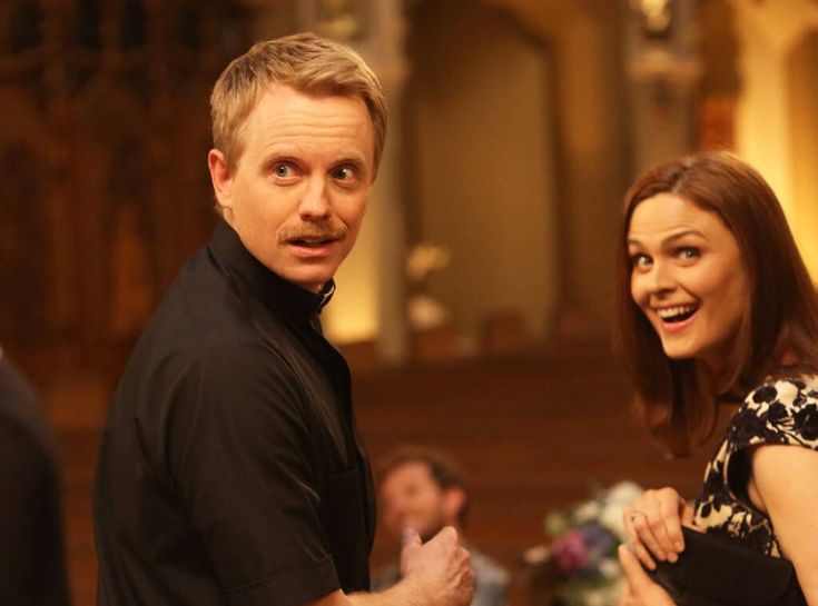 a man and woman standing next to each other in front of a church pews