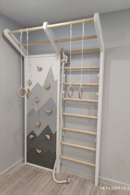 a room with a climbing wall and wooden ladders