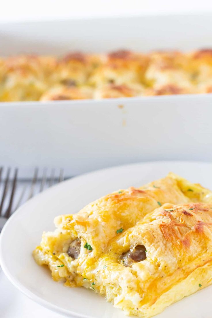 an omelet on a white plate next to a casserole dish with sausage