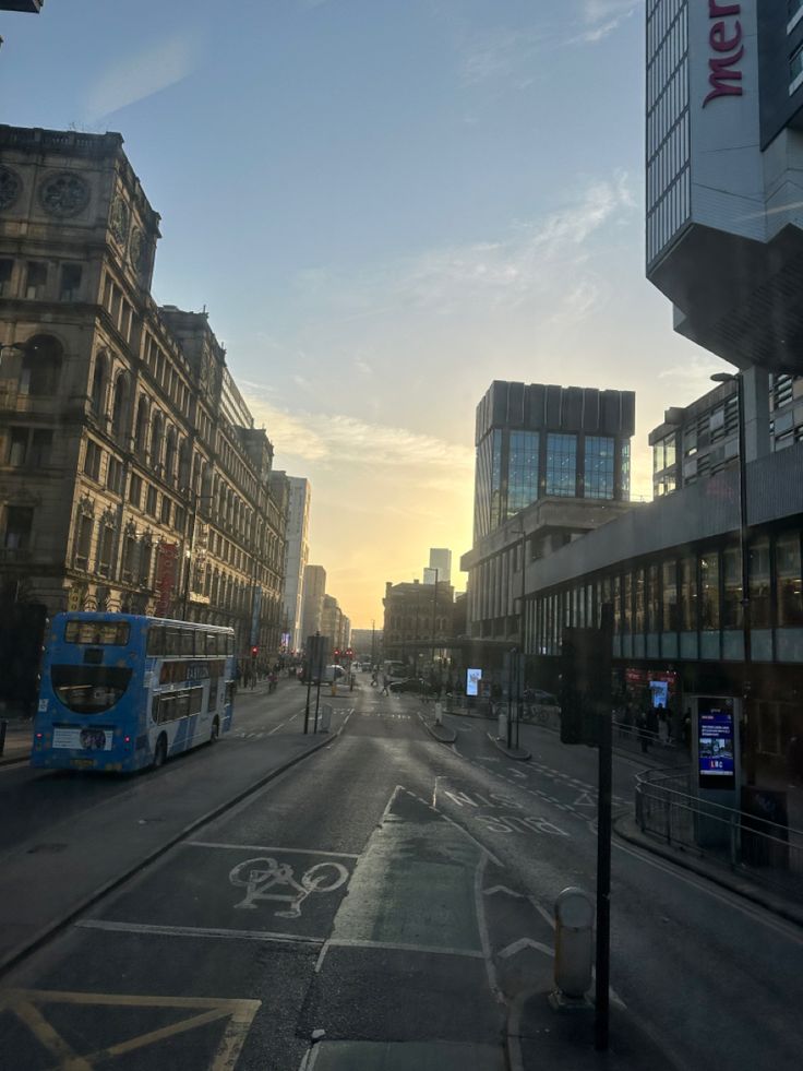 an empty city street at sunset with buildings in the back ground and a double decker bus on the road