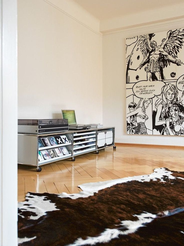 a living room filled with furniture and a comic strip wall hanging on the wall behind it