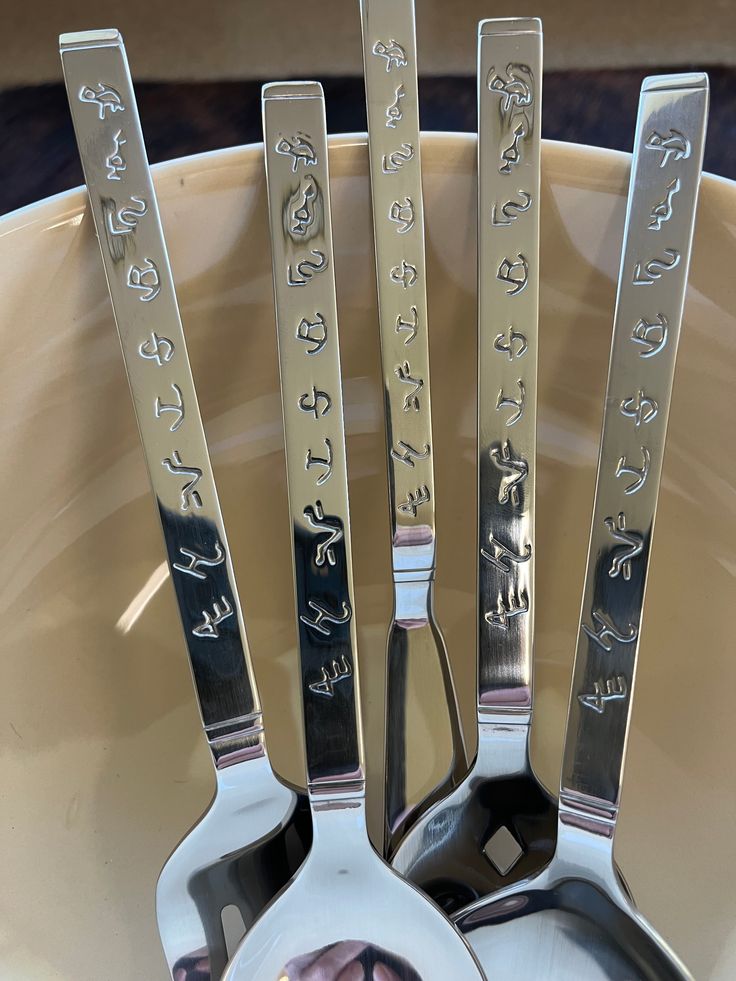 spoons and forks with pictures on them are in a bowl next to each other