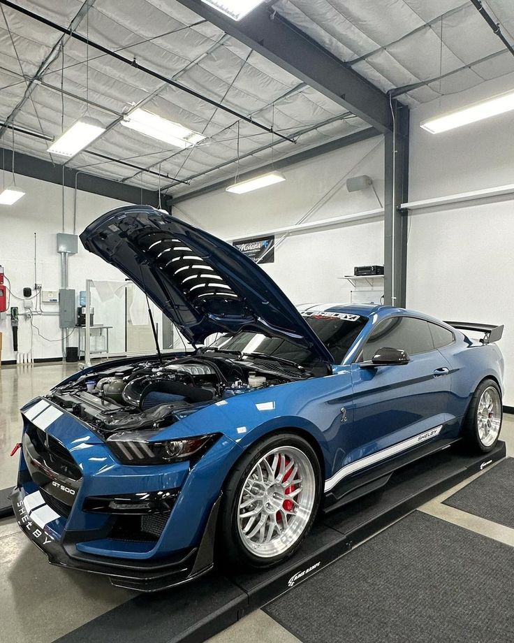 a blue car with its hood open in a garage