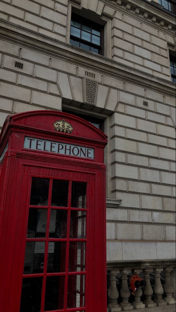 a red phone booth sitting in front of a tall building