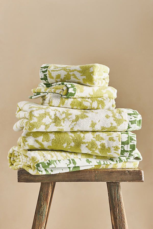 a stack of folded towels sitting on top of a wooden stool