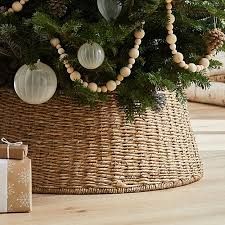 a christmas tree in a wicker basket with ornaments on it and a present underneath