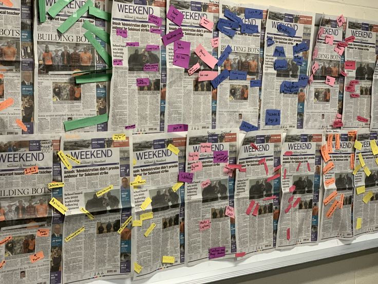 a bulletin board is covered with newspaper and pinned to it's sides in different colors