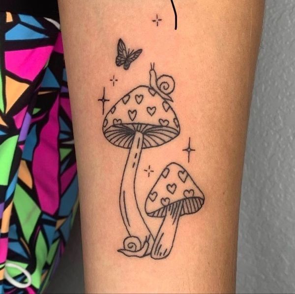 a small mushroom tattoo on the right arm with a butterfly flying over it and hearts in the air