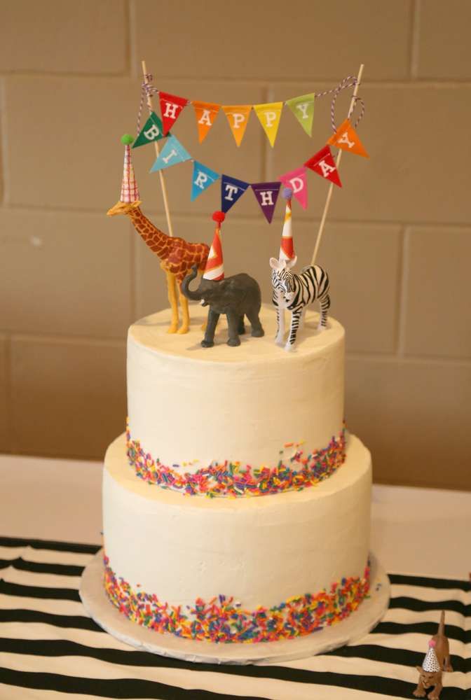 a birthday cake with an animal and giraffe topper on the bottom tier