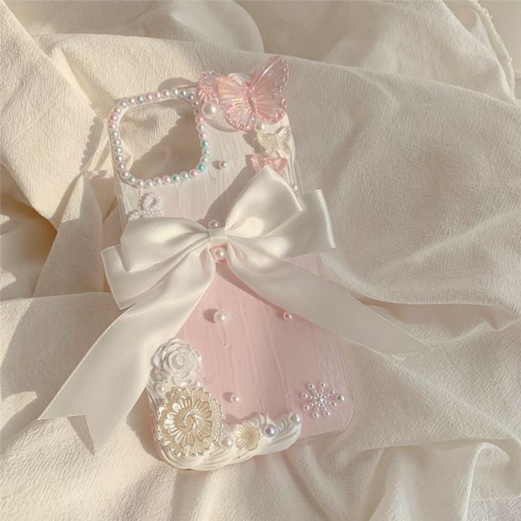 two pink and white cell phones are laying on a bed with a ribbon around them