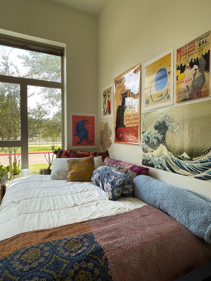 a large bed sitting in a bedroom next to a window with lots of pictures on the wall