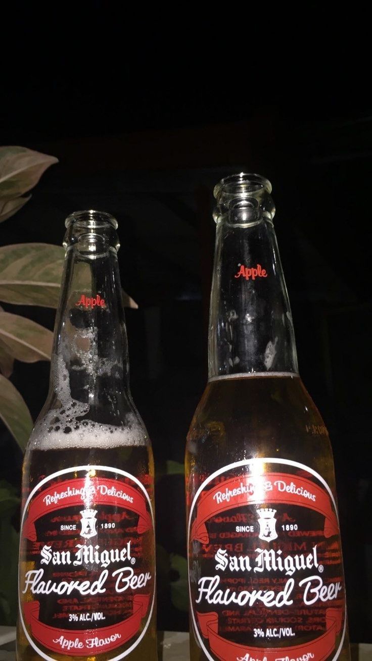 two bottles of san miguel flavored beer sitting next to each other on a table