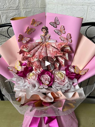 a bouquet made out of pink and white paper with butterflies on it, sitting on a table