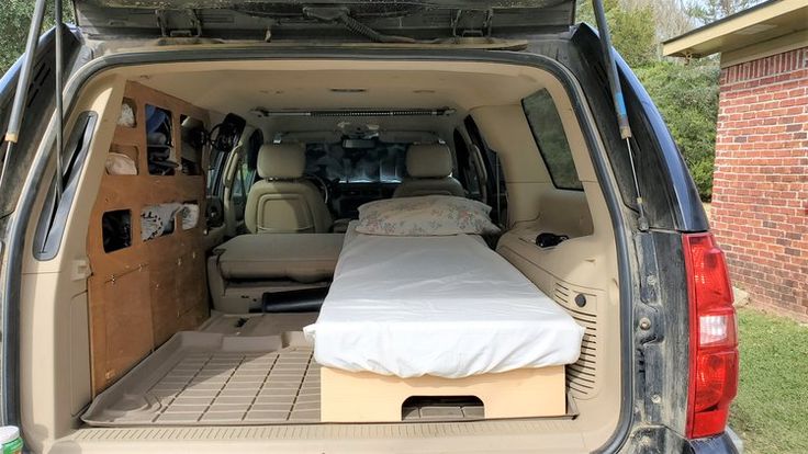 the back end of a van with a bed in it's cargo area and an open trunk door