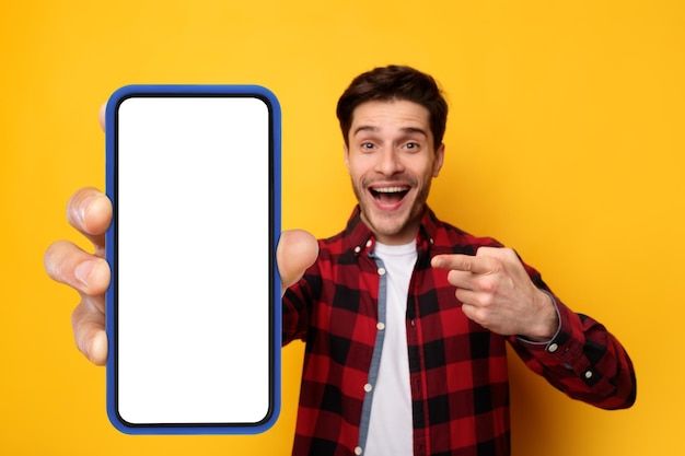 a man holding up a smart phone in front of his face and pointing at the screen